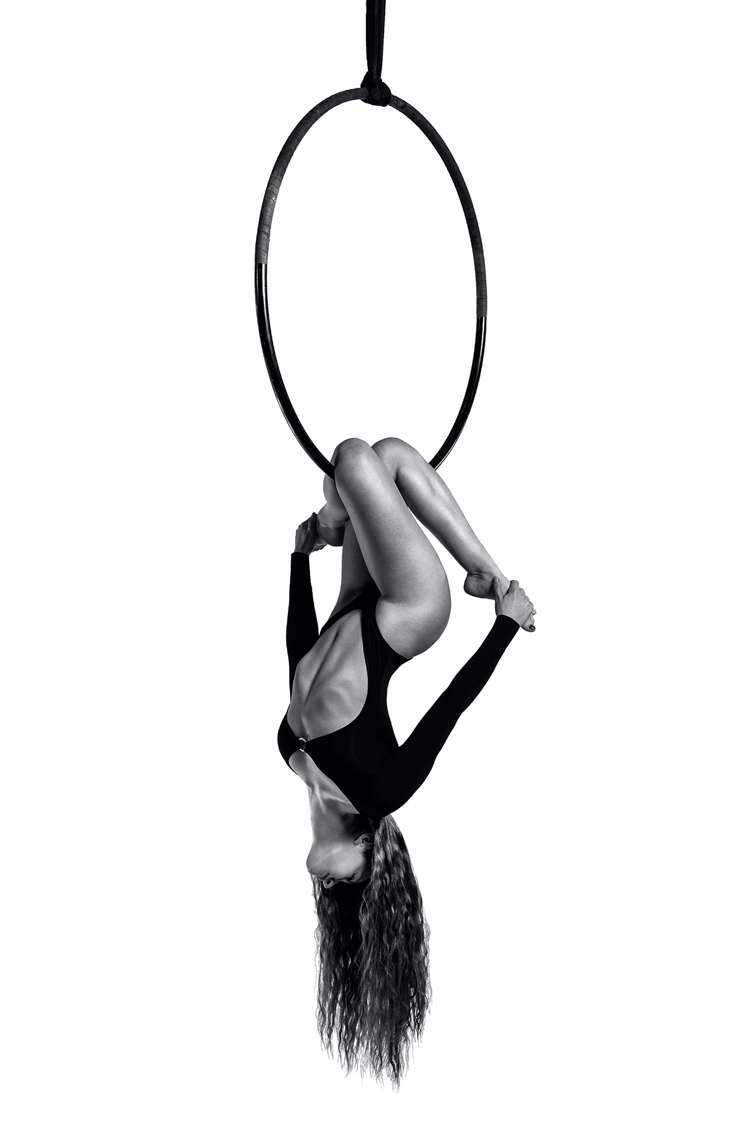 Aerialist inverted below the hoop, holding both feet.